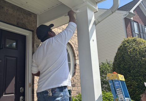 painter working on column outside house