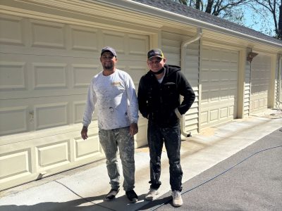 two painters standing in front of row of garages