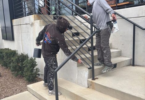 two painters working on outside stairway rails