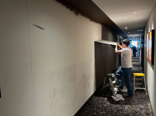 man removing wallpaper in hotel hallway Preview Image 2
