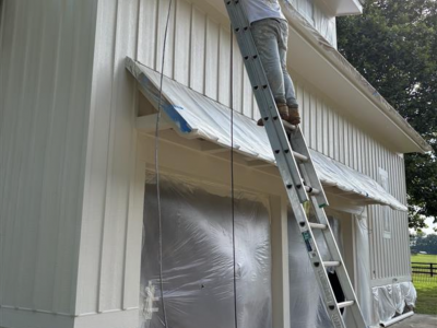 painter on a ladder painting siding on house