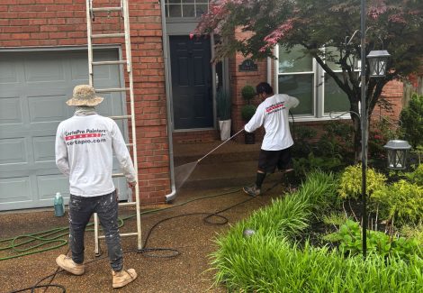 painters on ladders outside brick home