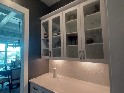 white kitchen counter and glass-front cabinet with dark painted walls