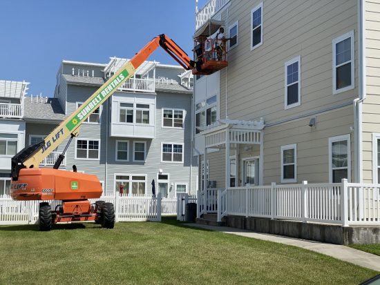 CertaPro Team Members painting condo exterior while standing on lift