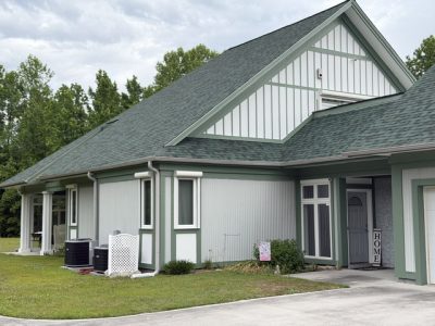 home exterior painted light sage green with darker green trim and accent areas