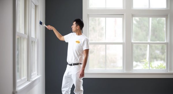 A painter is painting the interior of a room in a house.