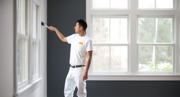 A painter is painting the interior of a room in a house.