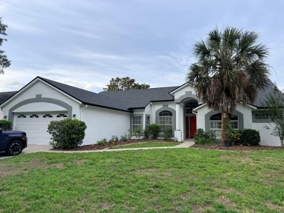 painted stucco house exterior with grey trim and red door