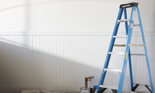 ladder and paint bucket in front of white wall