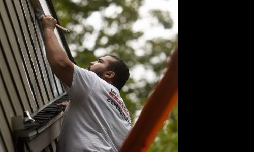 painter prepping siding to be painted