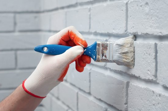 A person painting a brick white