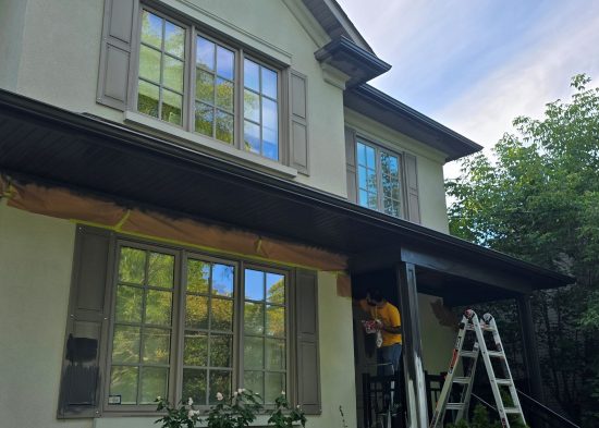 painter working on front exterior of hosue