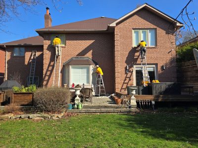 painting team on ladders against brick house exterior