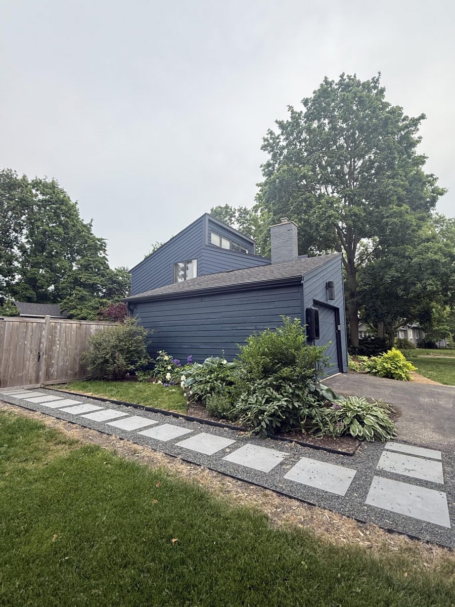 side of house with dark blue painted siding and paved path with landscaping Preview Image 1