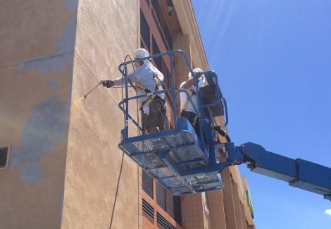 painters on boom lift spraying building exterior