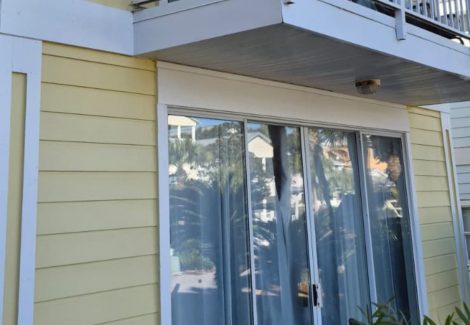 house with worn yellow siding and white balcony