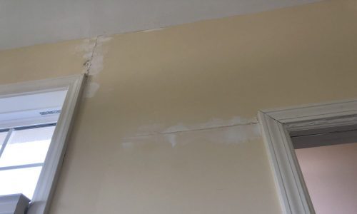 Drywall between window and door frame with a tension crack