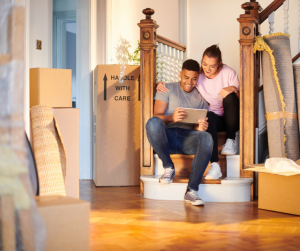 couple sitting on home stairs with boxes moving in to home