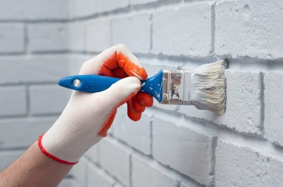 Person painting bricks with a paintbrush