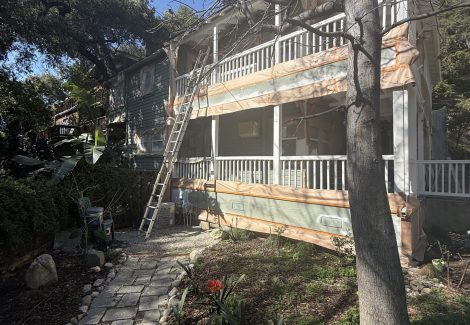 house with protective wrap during painting