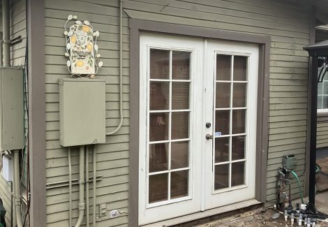 french doors of craftsman style house with damaged and worn siding