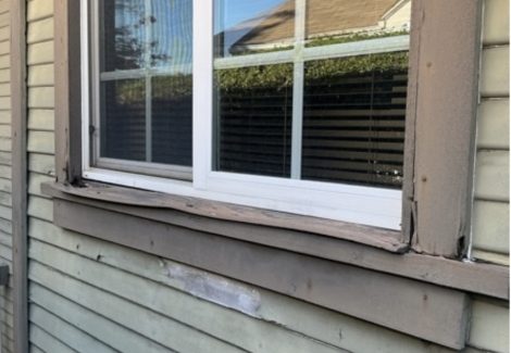 exterior view of house window with worn paint and siding