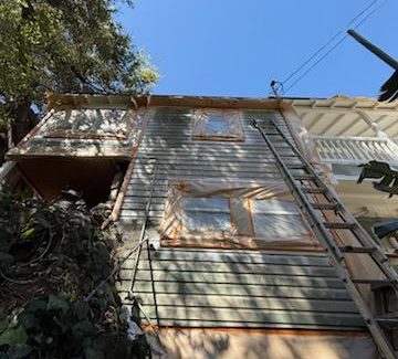 house with protective wrap during painting