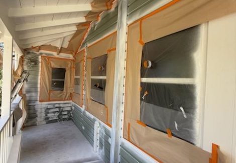 house with protective wrap during painting