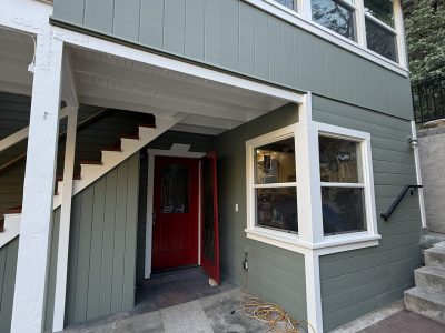 light green painted house with white trim and red door