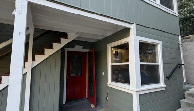 light green painted house with white trim and red door