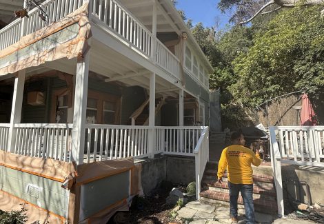 house with protective wrap during painting