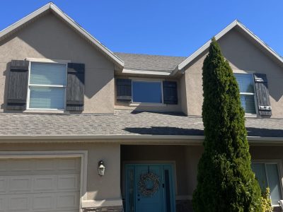 front exterior of stucco house with dark grey painted shutters