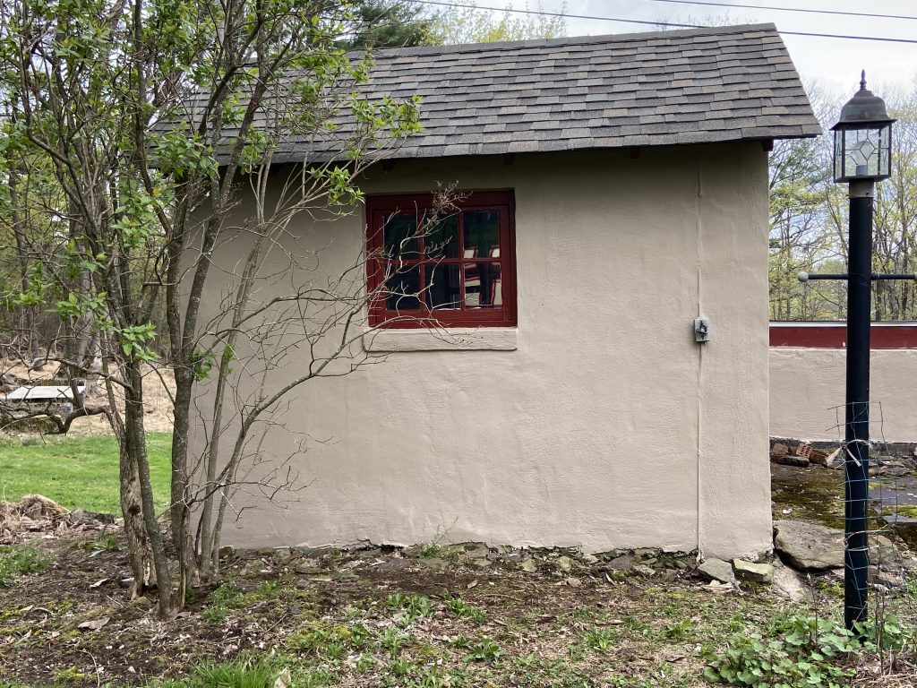 tan painted cement shed with maroon trim window