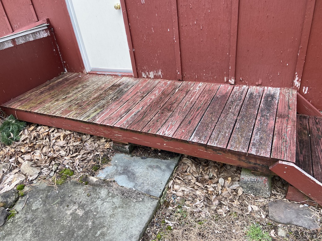 red worn down wood porch in front of barn