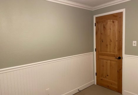 An interior bedroom with painted wainscoting and crown molding.