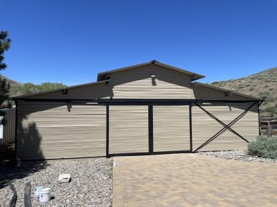 residential barn outbuilding with tan siding and black trim