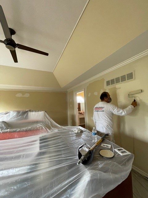 Professional painter rolling the walls with a light tan paint. Preview Image 1
