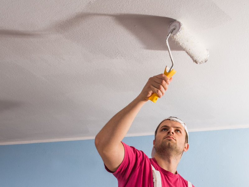 team member painting a white ceiling