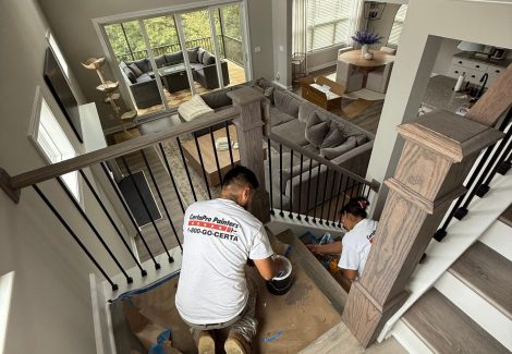 painters staining wooden staircase railing