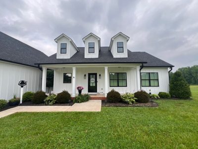 lawn and front of house with white siding and black roof