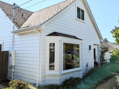 Home painted in Benjamin Moore Chantilly Lace which is a creamy white color. The home is cottage style and has a bay window in the front.