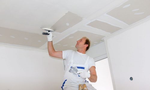 A painter repairing the drywall ceiling in a home before painting.