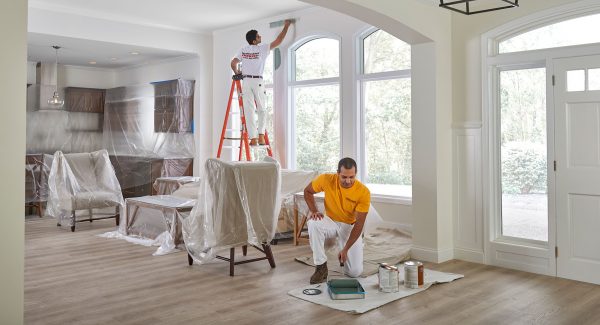 Two men painting the interior of a house