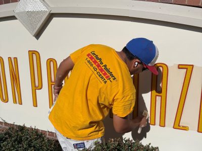 team member painting shopping center signage