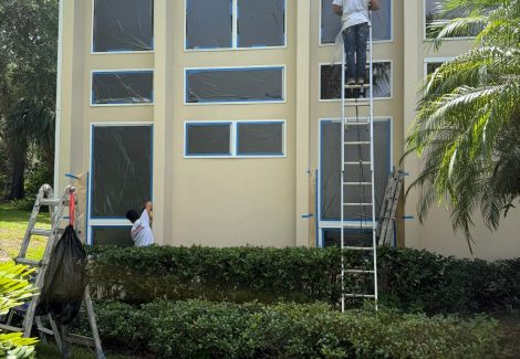person on ladder against house during window trim repaint