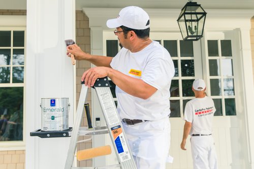 CertaPro Painter painting the details of a white house
