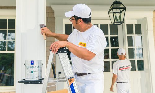 CertaPro Painter painting the details of a white house