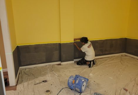 woman painting home interior wall with grey and yellow