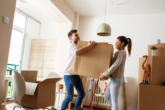 Man and woman lifting a box and moving in or out of home