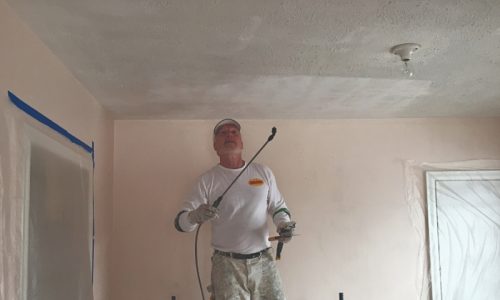 Popcorn ceiling removal services man spraying popcorn ceiling